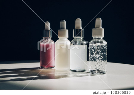 Four glass bottles with pipettes containing different cosmetic serums on table Four glass bottles with pipettes containing different cosmetic serums on table 138366839