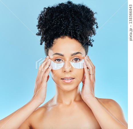 Portrait, woman and face with eye patch application for skin hydration glow, wellness or feel smooth beauty results. Spa salon, studio cosmetic or anti aging model with facial mask on blue background Portrait, woman and face with eye patch application for skin hydration glow, wellness or feel smooth beauty results. Spa salon, studio cosmetic or anti aging model with facial mask on blue background 138366843