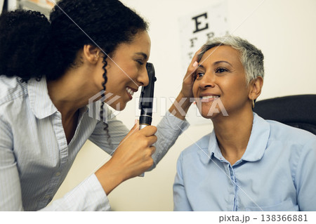 Woman, eyes and healthcare in clinic with ophthalmoscope to check glaucoma, ocular services or expert consultation. Optometrist, retina analysis and eye exam of happy mature patient with vision tools 138366881