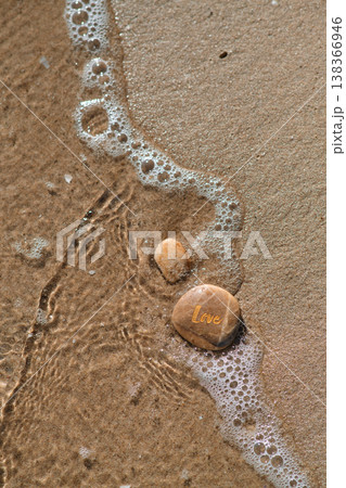 a stone with the inscription love on the coastal sand 138366946