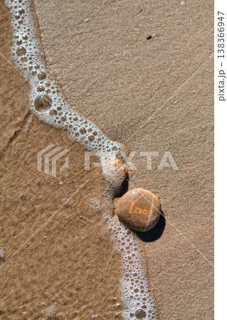 a stone with the inscription love on the coastal sand 138366947