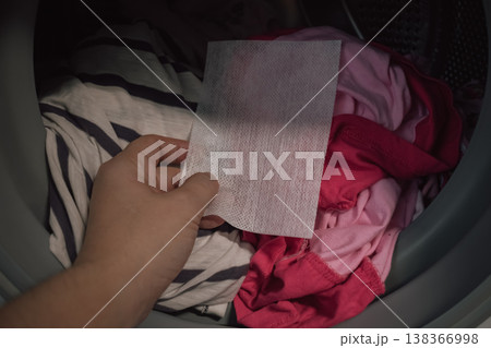 innovative color trap sheet close up in washing machine drum with pile of varied clothes 138366998