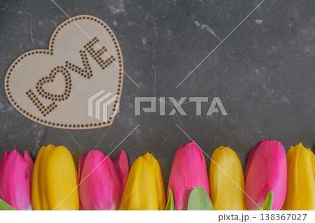 Vibrant yellow and pink tulips in a row on dark marble with a wooden LOVE heart. High-contrast Dark Moody composition with premium textures and large copy space Vibrant yellow and pink tulips in a row on dark marble with a wooden LOVE heart. High-contrast Dark Moody composition with premium textures and large copy space 138367027