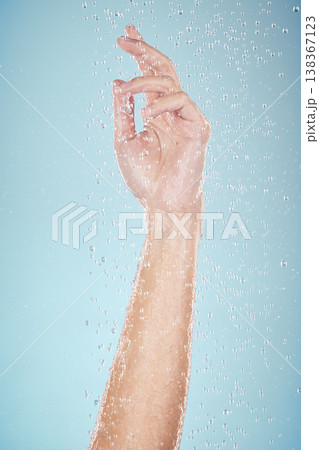 Water drops, hand and closeup with cleaning, shower and morning dermatology in studio. Blue background, person arm and splash for wellness, washing and skin glow with self care and hygiene safety Water drops, hand and closeup with cleaning, shower and morning dermatology in studio. Blue background, person arm and splash for wellness, washing and skin glow with self care and hygiene safety 138367123