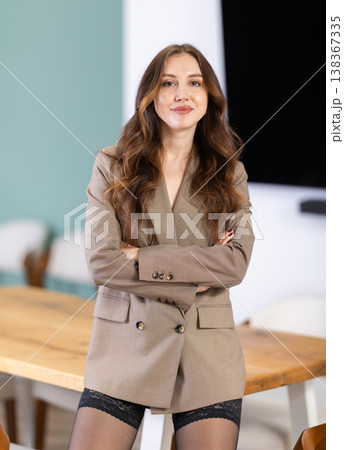 Half-naked topless girl in string underwear pants and blazer poses standing next to table 138367335