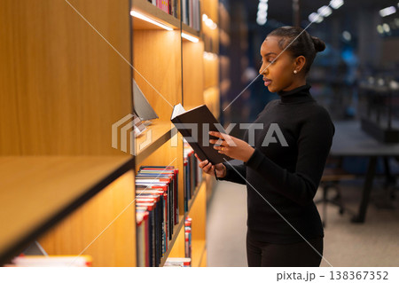 Woman reading a book in library 138367352