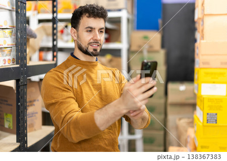 Young man scanning boxes in grocery warehouse Young man scanning boxes in grocery warehouse 138367383