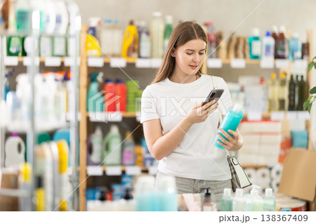 Checking expiration date of shampoo or shower gel - female shopper scans QR code on label of shampoo using smartphone 138367409