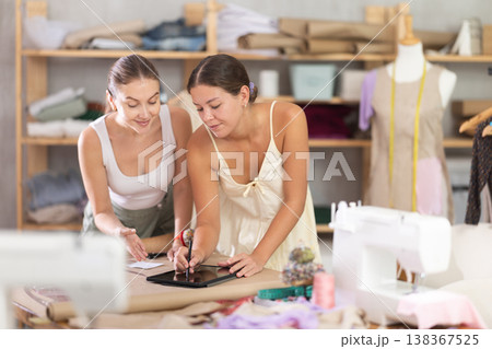 Two young female dressmakers drawing on tablet 138367525