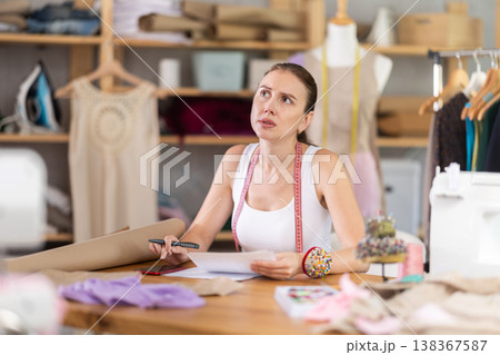 Young tailoress engaged in paperwork in sewing...の写真素材 [138367587] - PIXTA
