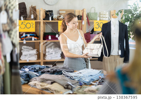 Young woman choosing handbag in fashion store Young woman choosing handbag in fashion store 138367595