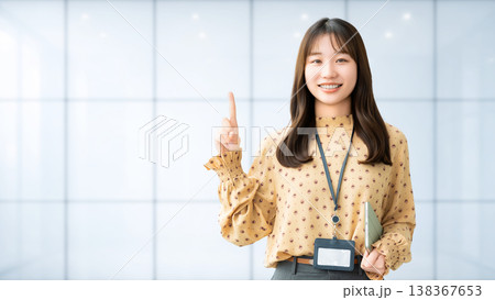 人差し指を立てて案内する若い女性・ビジネスウーマン 人差し指を立てて案内する若い女性・ビジネスウーマン 138367653