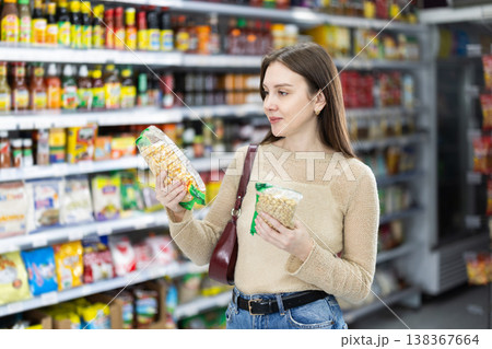 Young woman chooses beans at grocery store 138367664