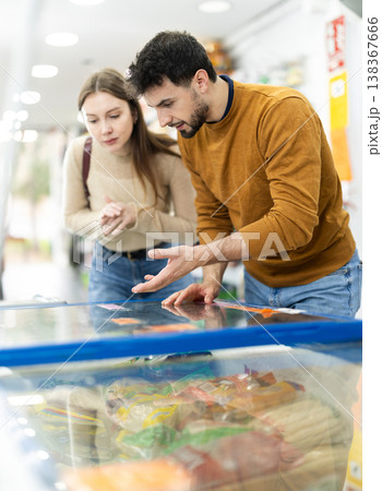 Couple spends time in store, looking for necessary goods and get out from refrigerator 138367666