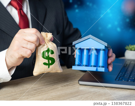 A businessman holds a bank and a dollar bag symbolizing deposits and loans. Financing solutions for business. Credit access, restructuring, and capital management support growth and stability A businessman holds a bank and a dollar bag symbolizing deposits and loans. Financing solutions for business. Credit access, restructuring, and capital management support growth and stability 138367822