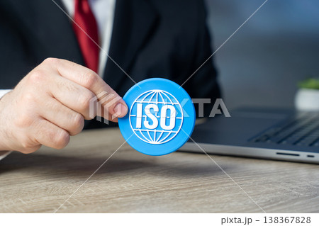 A businessman holds an ISO sign showing compliance with standards. Quality management systems ensure reliability. Certification, regulation, and corporate governance support operational excellence A businessman holds an ISO sign showing compliance with standards. Quality management systems ensure reliability. Certification, regulation, and corporate governance support operational excellence 138367828