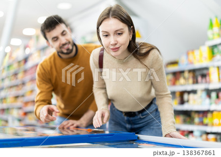 Couple spends time in store, looking for necessary goods and get out from refrigerator 138367861
