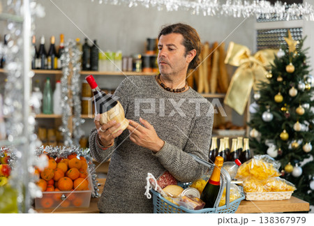 Man choosing wine in grocery store adorned for Christmas Man choosing wine in grocery store adorned for Christmas 138367979