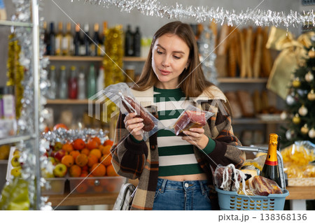 Woman with grocery cart choosing dried sausage and jamon for Christmas or New Year celebration in produce section of supermarket Woman with grocery cart choosing dried sausage and jamon for Christmas or New Year celebration in produce section of supermarket 138368136