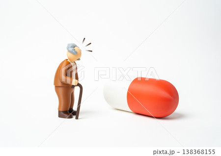 An elderly man surprised by a large pill highlights complex treatment. Multiple medications and healthcare routines define aging. Pharmaceutical dependence raises awareness of medical management An elderly man surprised by a large pill highlights complex treatment. Multiple medications and healthcare routines define aging. Pharmaceutical dependence raises awareness of medical management 138368155