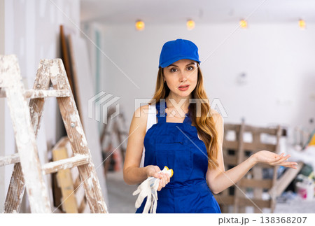 Portrait of builder woman in blue overalls next to stepladder Portrait of builder woman in blue overalls next to stepladder 138368207