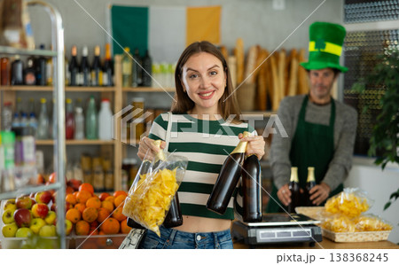 Cheerful woman shopping for beer and snacks in St. Patrick Day-themed store 138368245