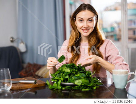 Young woman sorts fresh spinach 138368246