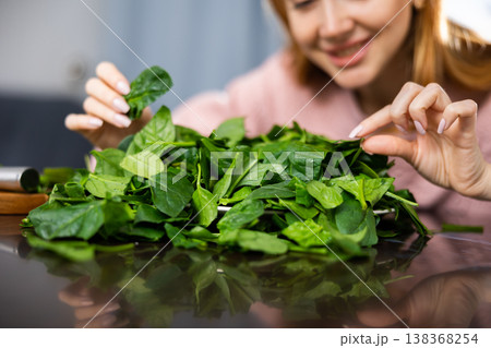 Girl carefully examines spinach leaves for salad 138368254