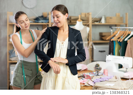 Female seamstress puts on jacket for girl client Female seamstress puts on jacket for girl client 138368321