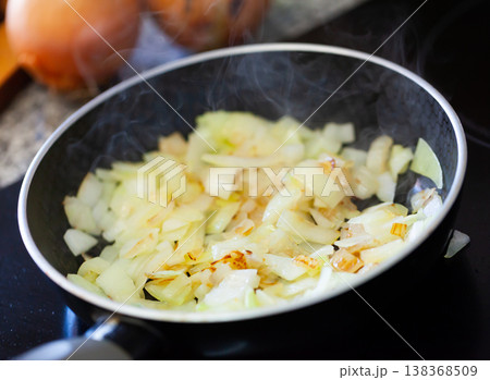 Chopped onions are fried in a black pan Chopped onions are fried in a black pan 138368509