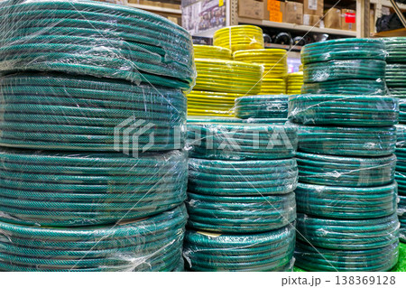 Coiled garden hoses stacked in hardware store display with colorful irrigation supplies Coiled garden hoses stacked in hardware store display with colorful irrigation supplies 138369128
