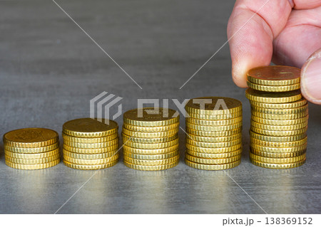 Stacked coins increasing with hand placing money growth savings investment finance concept Stacked coins increasing with hand placing money growth savings investment finance concept 138369152
