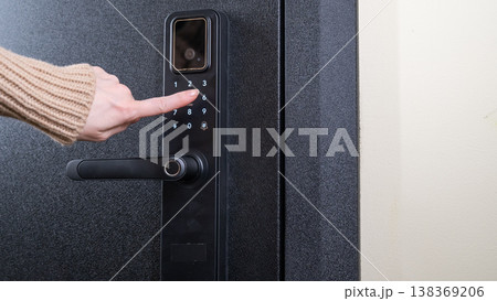 A woman opens a modern smart door lock with a digital keypad using a code. A woman opens a modern smart door lock with a digital keypad using a code. 138369206