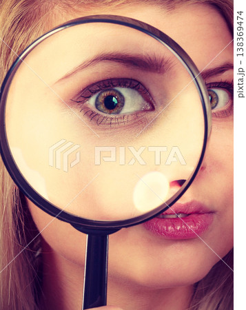 Woman looking through magnifying glass Woman looking through magnifying glass 138369474