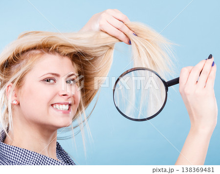 Woman looking at hair through magnifying glass Woman looking at hair through magnifying glass 138369481