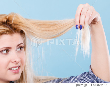 Blonde woman holding her hair ends Blonde woman holding her hair ends 138369482