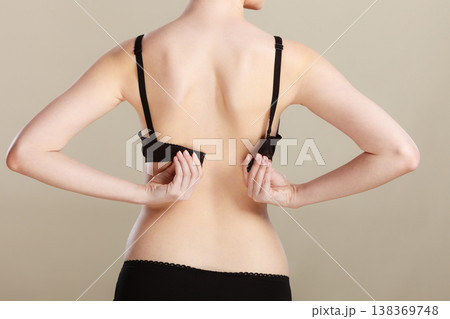 Woman dressing up her bra rear view Woman dressing up her bra rear view 138369748