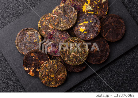 Organic Chinese green pu-erh tea with various herbs in round bricks. Chinese pu-erh tea Organic Chinese green pu-erh tea with various herbs in round bricks. Chinese pu-erh tea 138370068