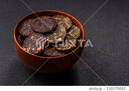 Organic Chinese green pu-erh tea with various herbs in round bricks. Chinese pu-erh tea Organic Chinese green pu-erh tea with various herbs in round bricks. Chinese pu-erh tea 138370082