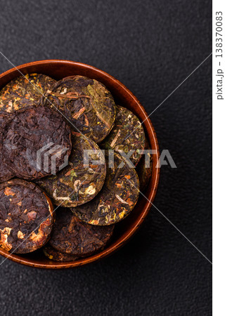 Organic Chinese green pu-erh tea with various herbs in round bricks. Chinese pu-erh tea Organic Chinese green pu-erh tea with various herbs in round bricks. Chinese pu-erh tea 138370083