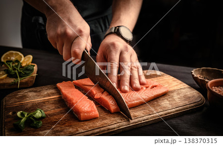 chief cutting a salmon fillet into pieces for cooking chief cutting a salmon fillet into pieces for cooking 138370315