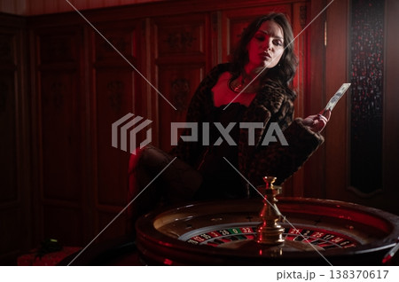 A beautiful brunette in a black dress at the casino roulette wheel. A beautiful brunette in a black dress at the casino roulette wheel. 138370617