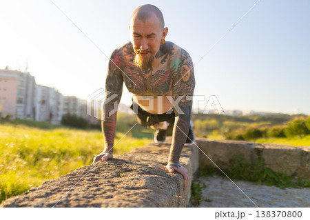 Tattooed man doing push up exercise outdoors Tattooed man doing push up exercise outdoors 138370800