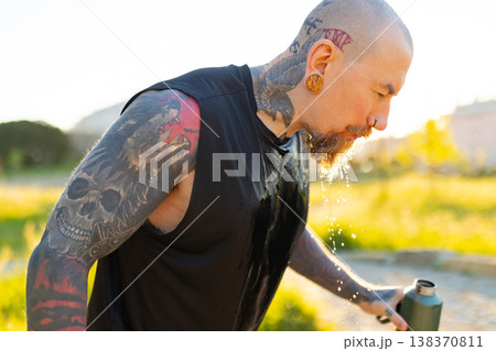 Tattooed man cooling down spitting water outdoors 138370811