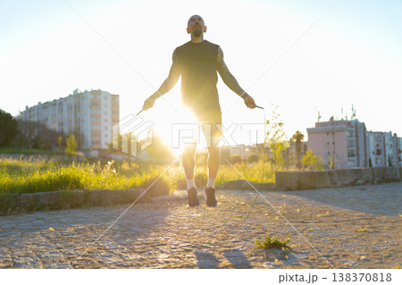 Determined man jumping rope outdoors at sunset Determined man jumping rope outdoors at sunset 138370818