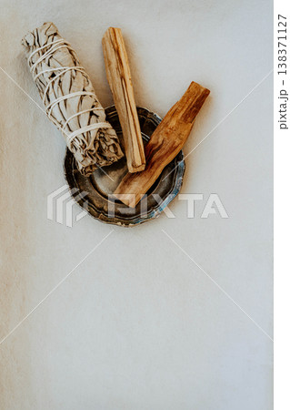 White sage bundle and palo santo sticks in metal dish on white background 138371127