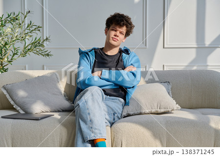 Portrait of handsome young man with curly hair sitting on sofa Portrait of handsome young man with curly hair sitting on sofa 138371245