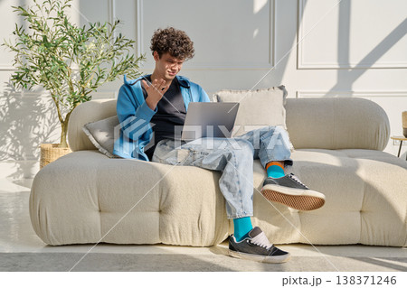 Young man using laptop for video call, online chat conference sitting at home Young man using laptop for video call, online chat conference sitting at home 138371246