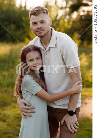 Father Holds Daughter In Field. Loving Father Embraces Daughter In Peaceful Outdoor Setting 138371395