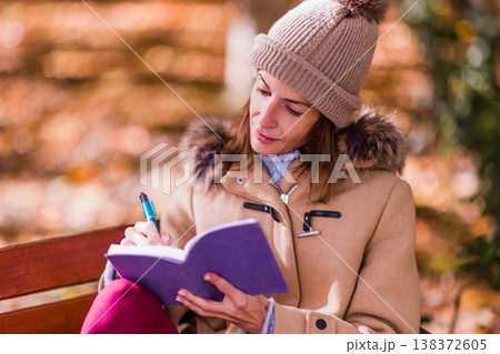 Woman writing personal diary for mental health support outdoors Woman writing personal diary for mental health support outdoors 138372605